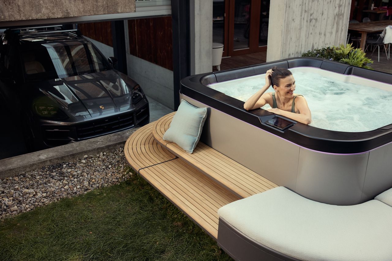 A woman relaxing in the SP—116 next to a Porsche in the garage